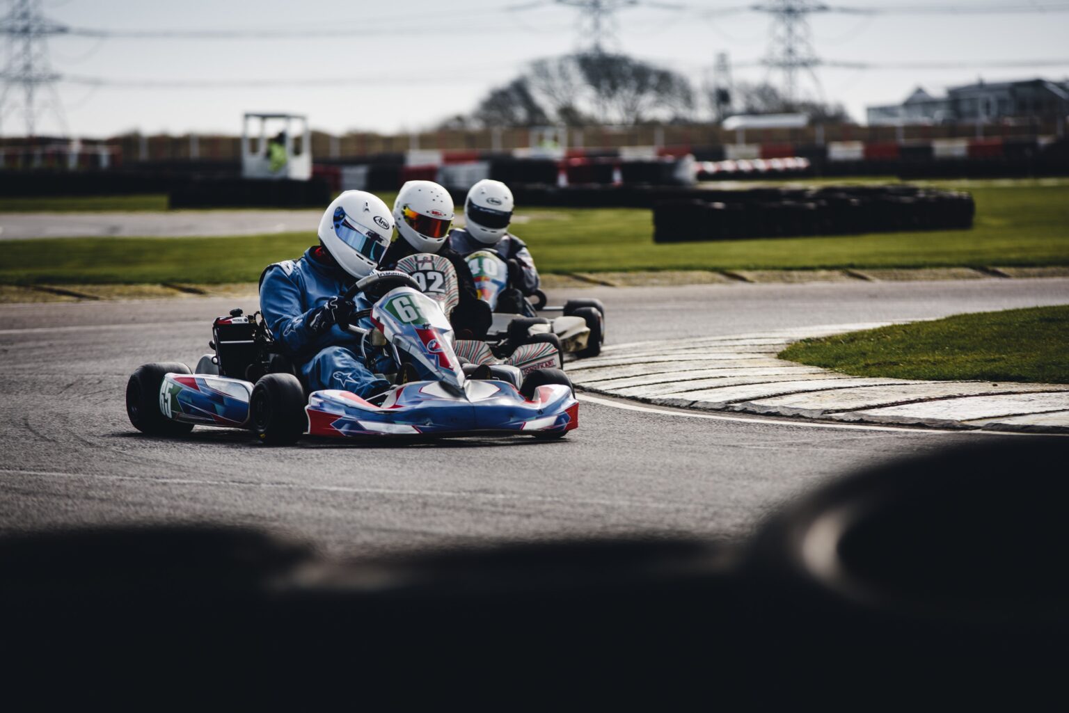 3 people racing go karts around a corner on a track