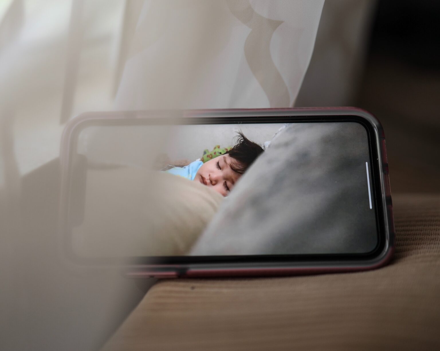 A closeup of a phone with a baby sleeping on the screen