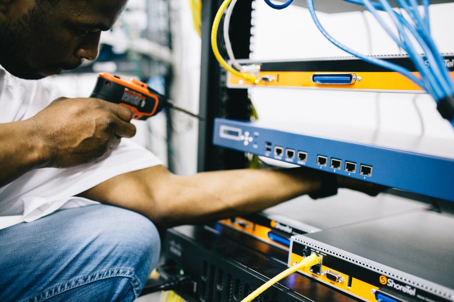 A man using an Electric Screwdriver on networking servers