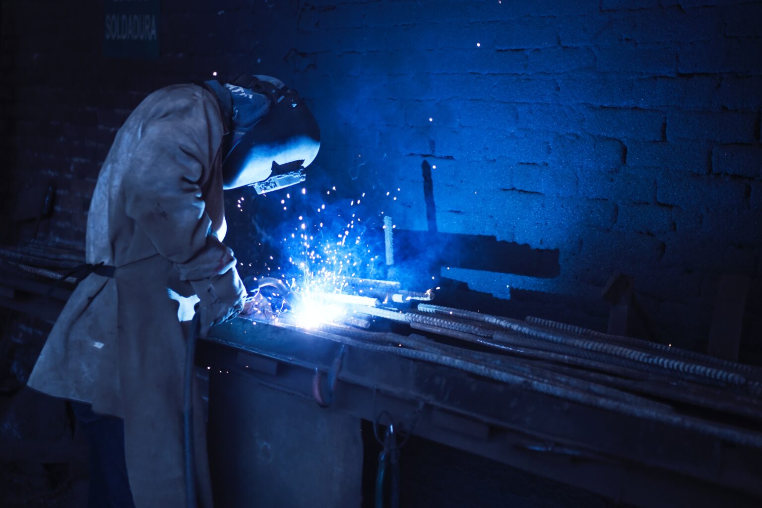 A man using an AC/DC TIG Welder UK to weld metal rods wearing a welding mask