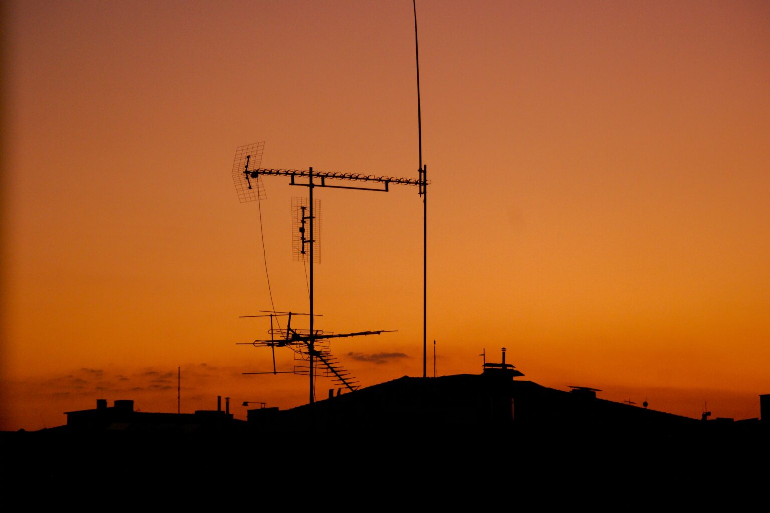 An Outdoor TV Aerial on a roof with a lovely orange sky behind it