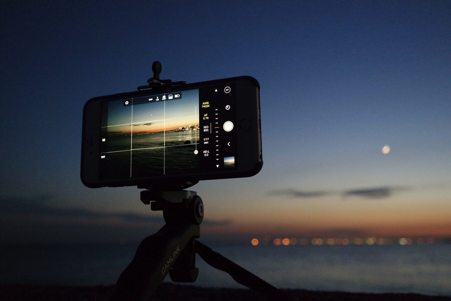 A phone with a microphone attached on a tripod recording a sunset