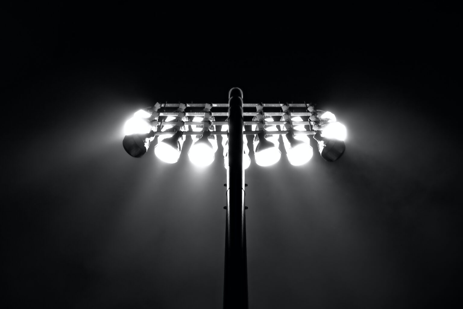 A black and white picture of a large LED floodlight with the sky behind it