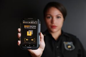 A woman in uniform holding up a body worn camera