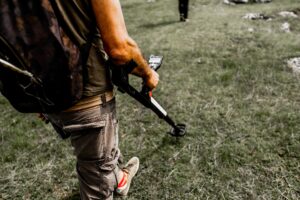 A closeup of a man using a metal detector in a field