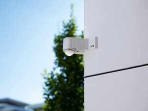 A PIR sensor on the corner of a building with the sky in the background