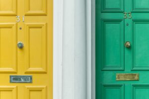 A yellow front door and a green front door next to each other