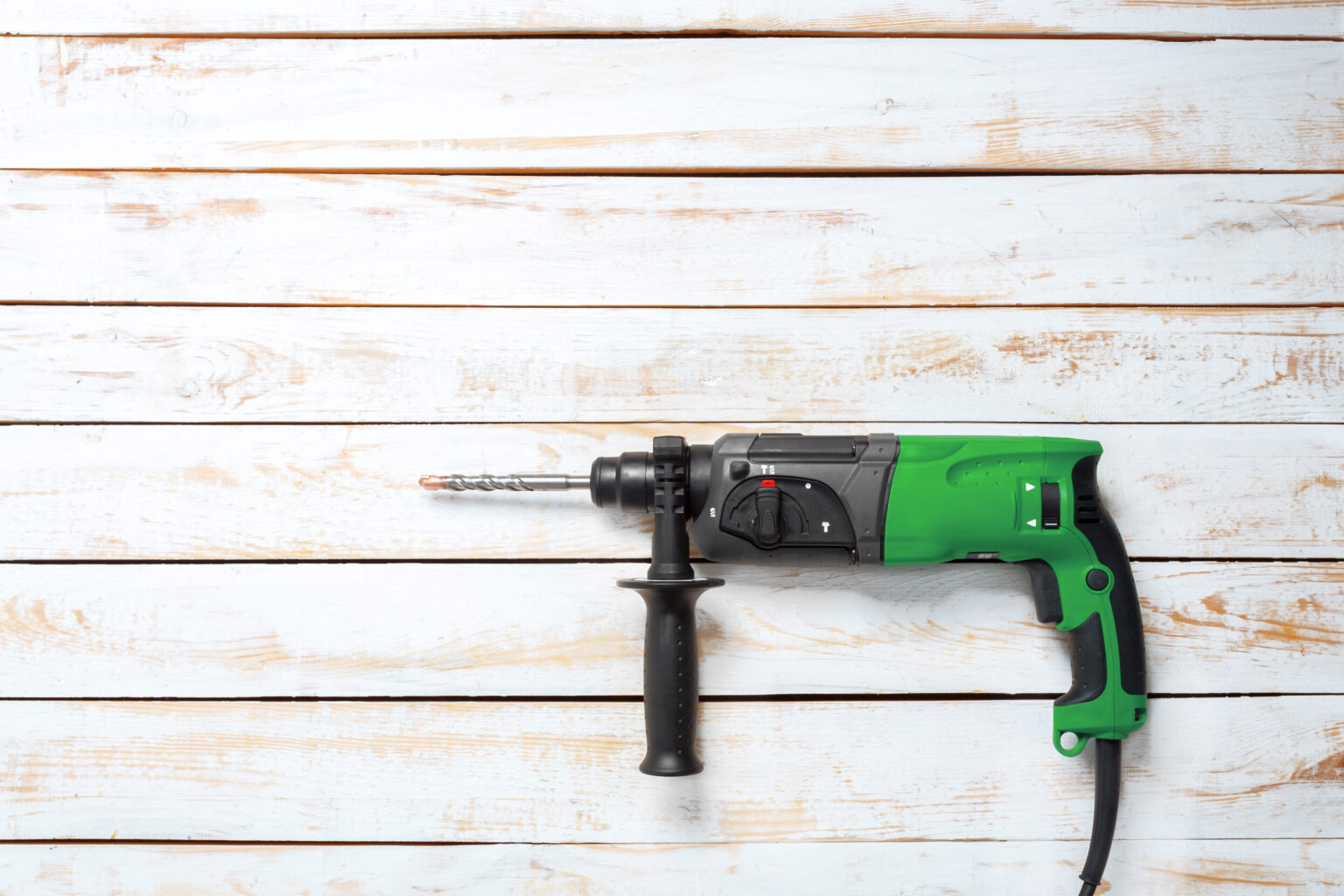 A Corded Hammer Drill on light wooden planks