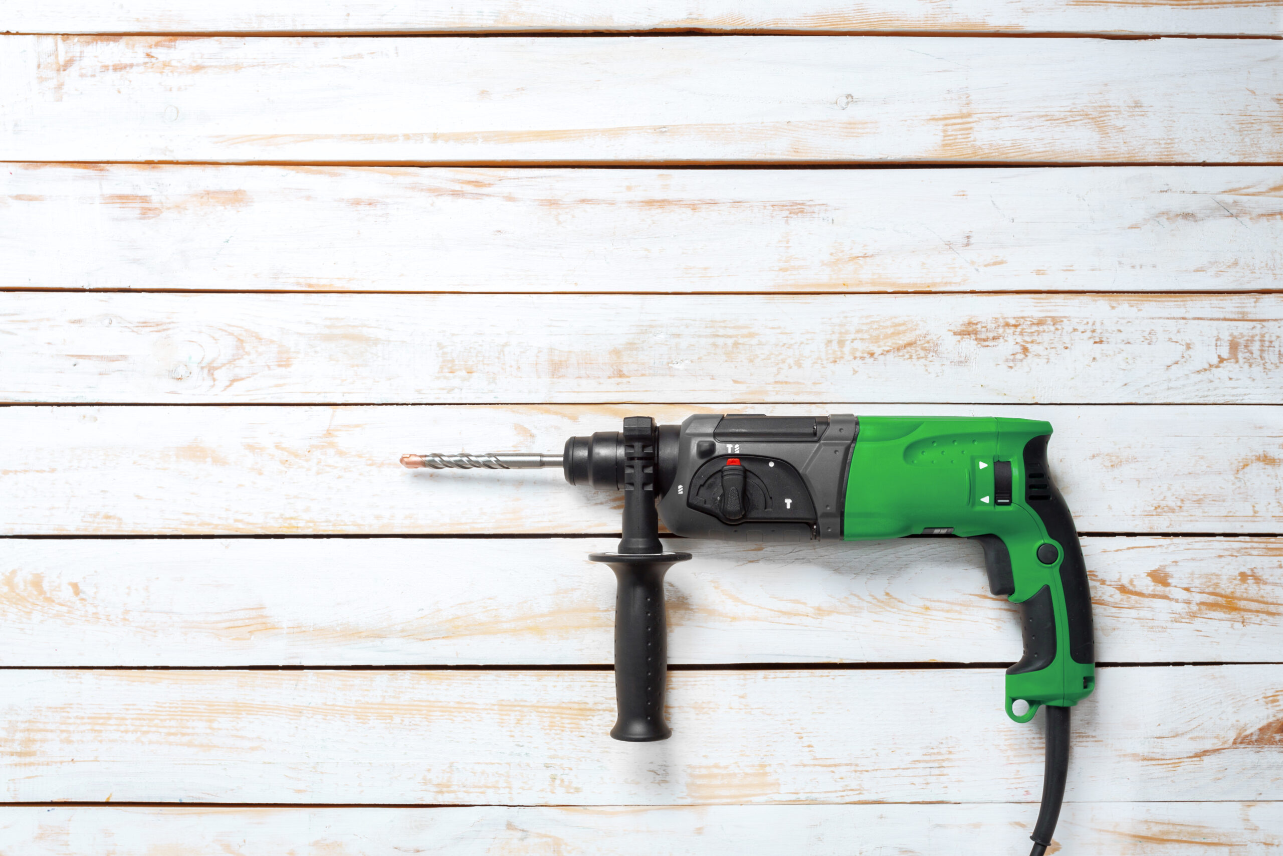 A Corded Hammer Drill on light wooden planks