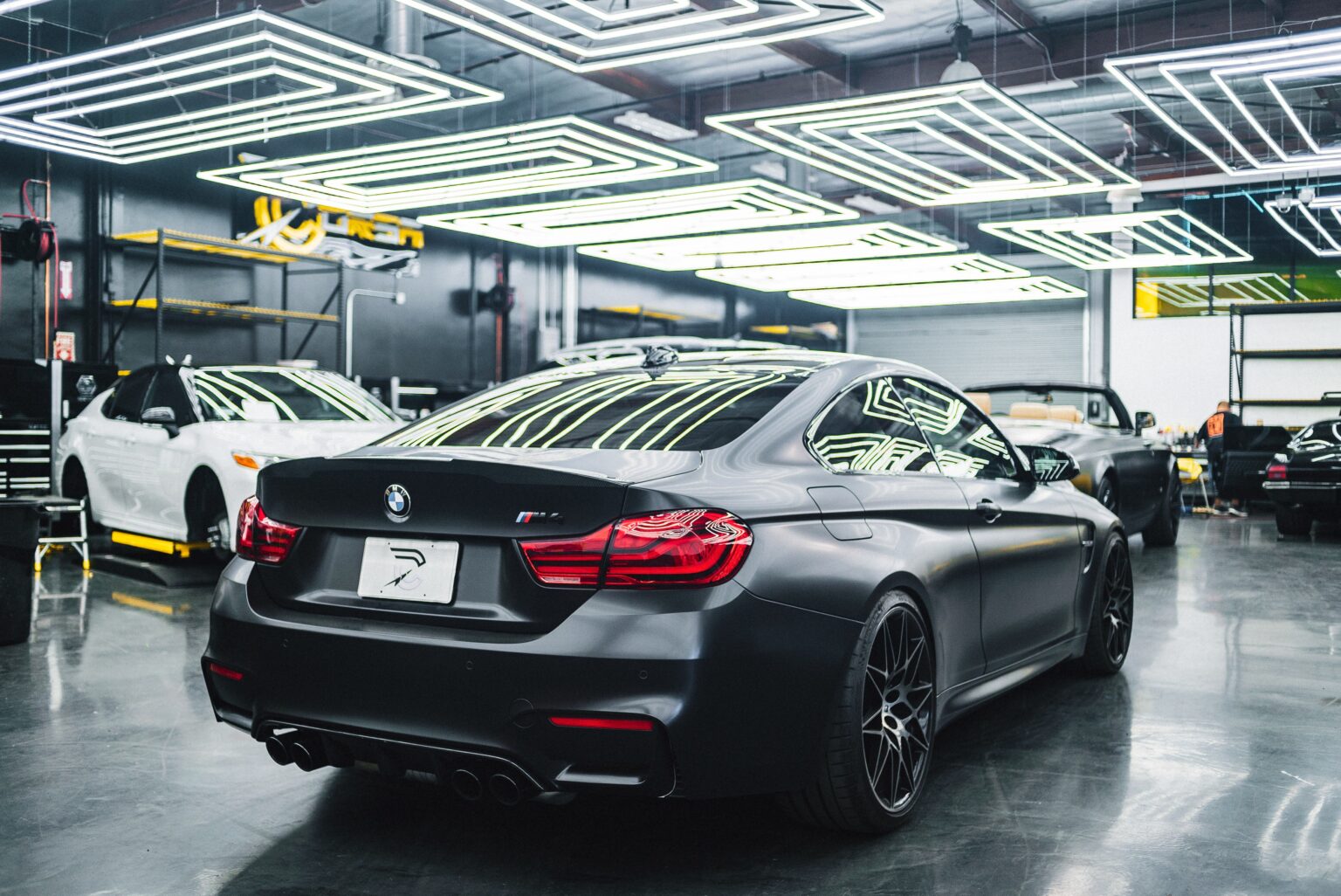 A BMW M4 in a workshop with LED lights overhead