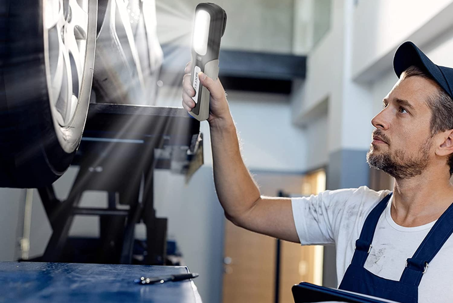 A man using an LED Rechargeable Inspection Lamp to examine a car