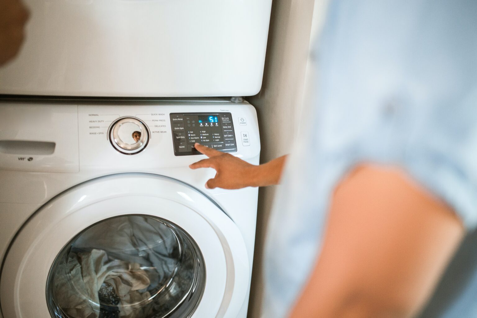 A man pressing the buttons on a washing machine