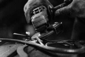 A black and whit picture of a man using a Cordless Angle Grinder to grind metal