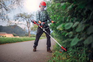 A man using a Cordless Brush Cutter to trim grass next to a path