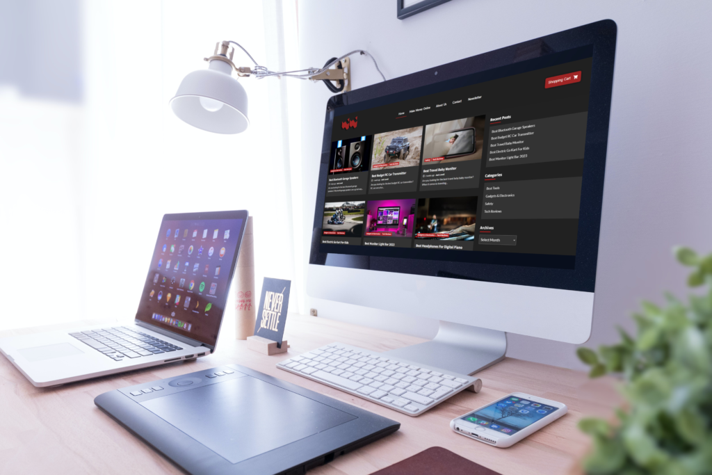 An iMac on a desk with the Trailblazing Tech homepage on the screen next to a macbook and an iPhone