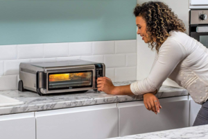 A woman in a kitchen using a mini oven