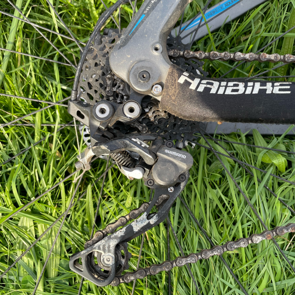 A closeup of the Shimano SLX M 675 Shadow Plus 10-speed Transmission with grass in the background