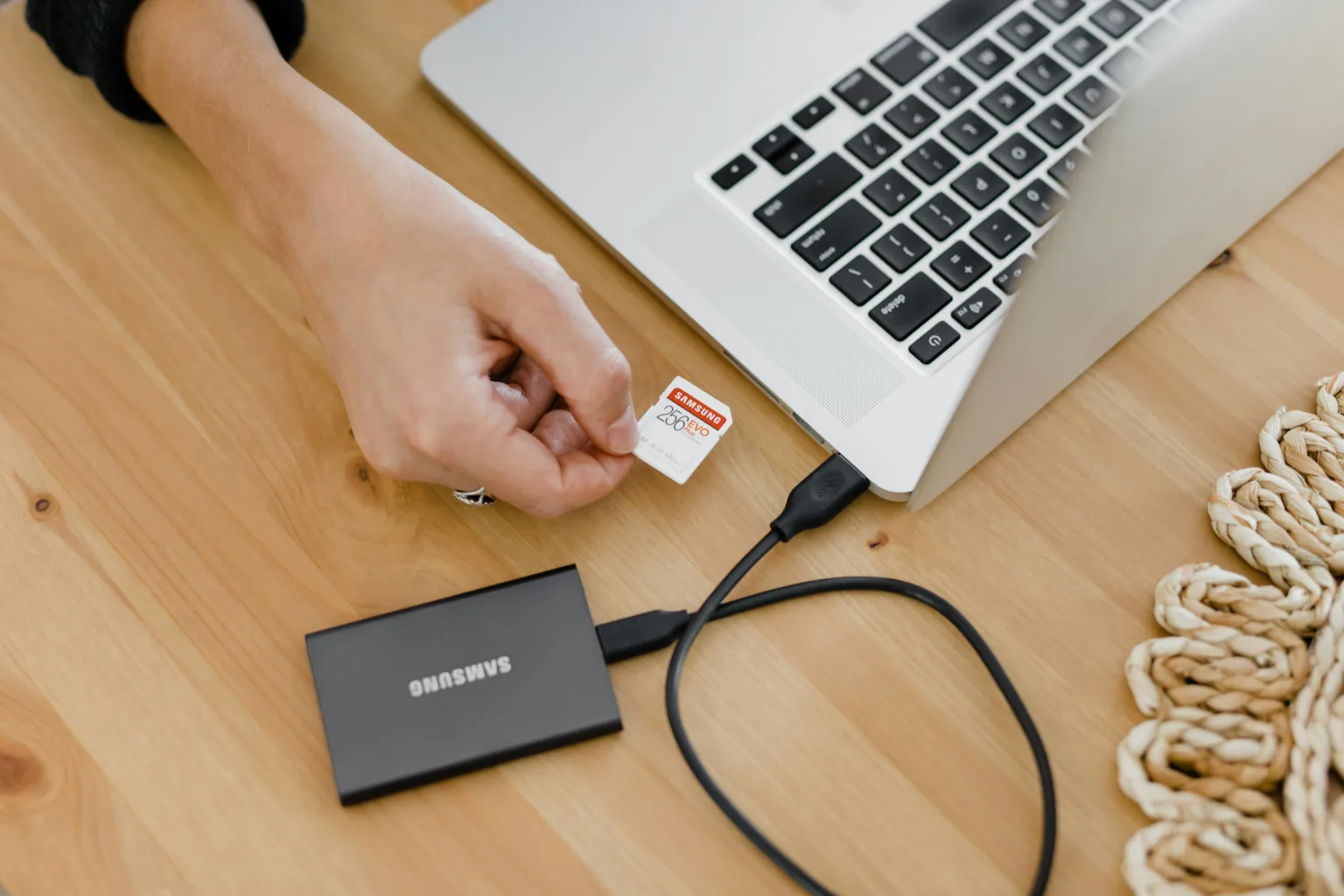 A Micro SD to SD Memory Card Adapter plugged in to a laptop with a hand holding an SD card