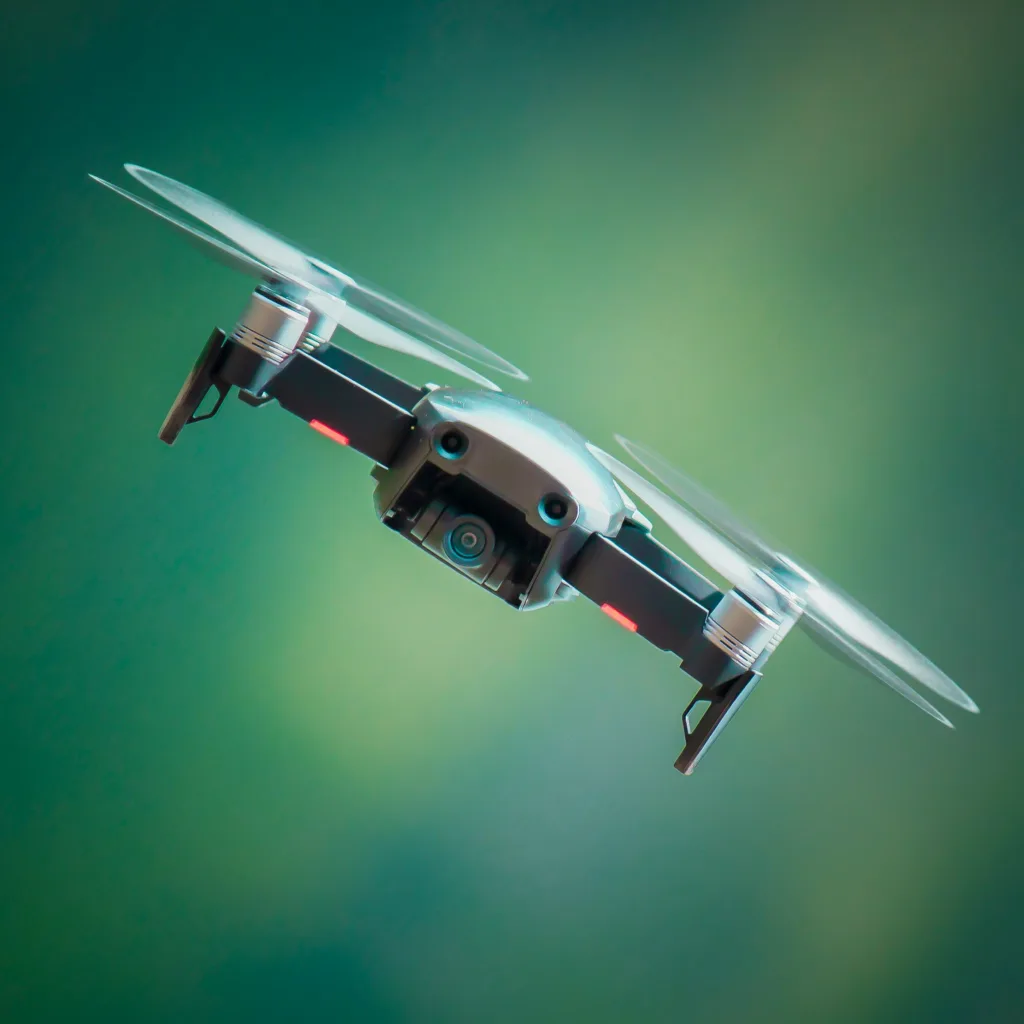 A drone flying at an angle with a blurry green background