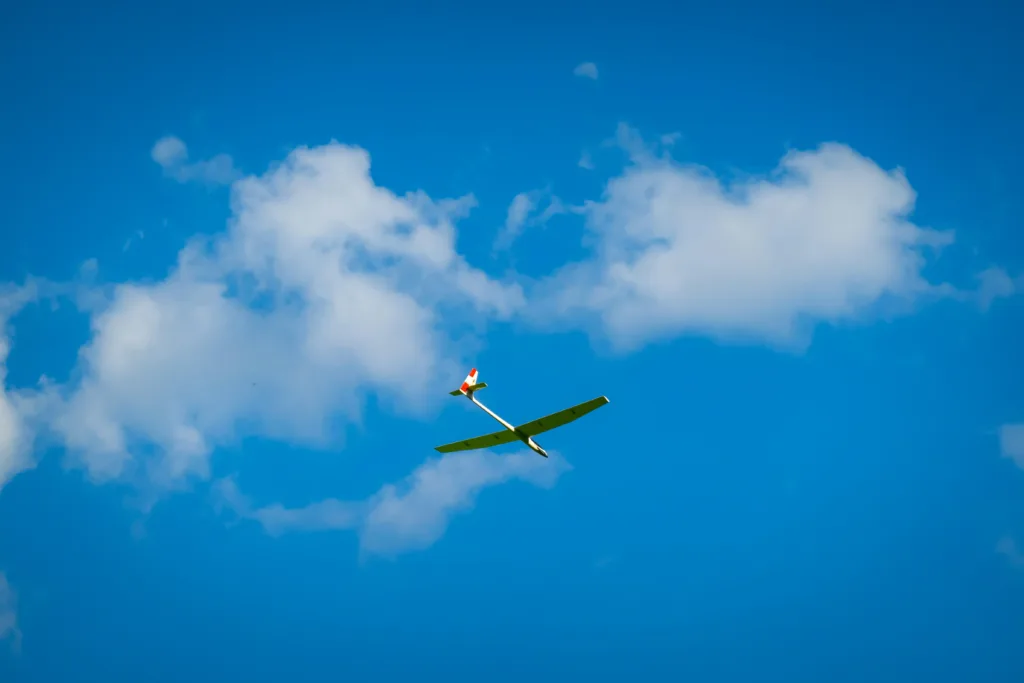 An rc plane flying with clouds in the background