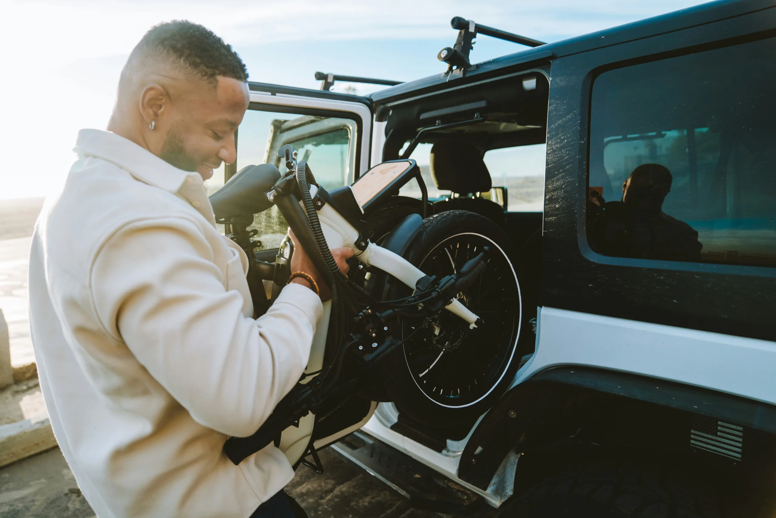 A man putting a folded ebike in to the back of a car