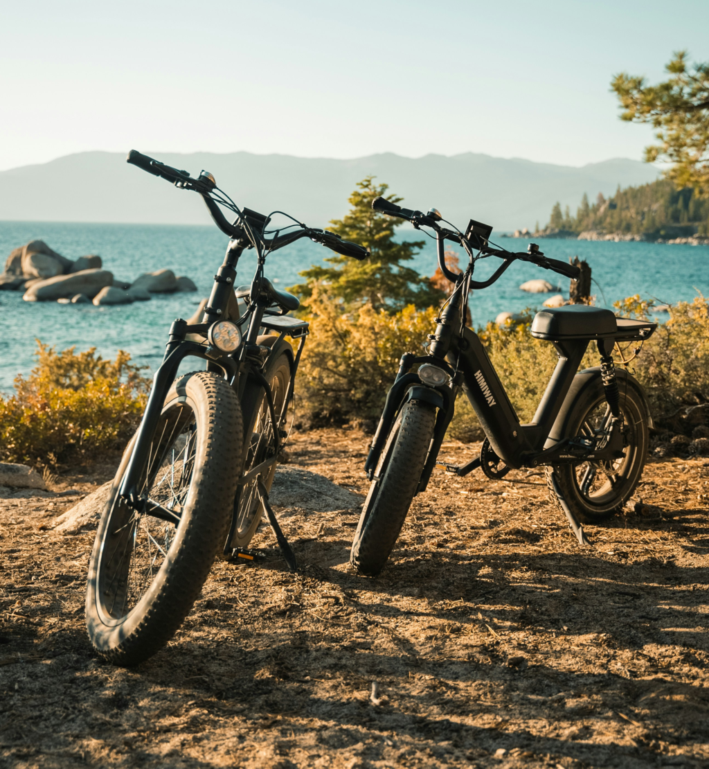 Two electric bikes on the beach with sea and mountains in the background