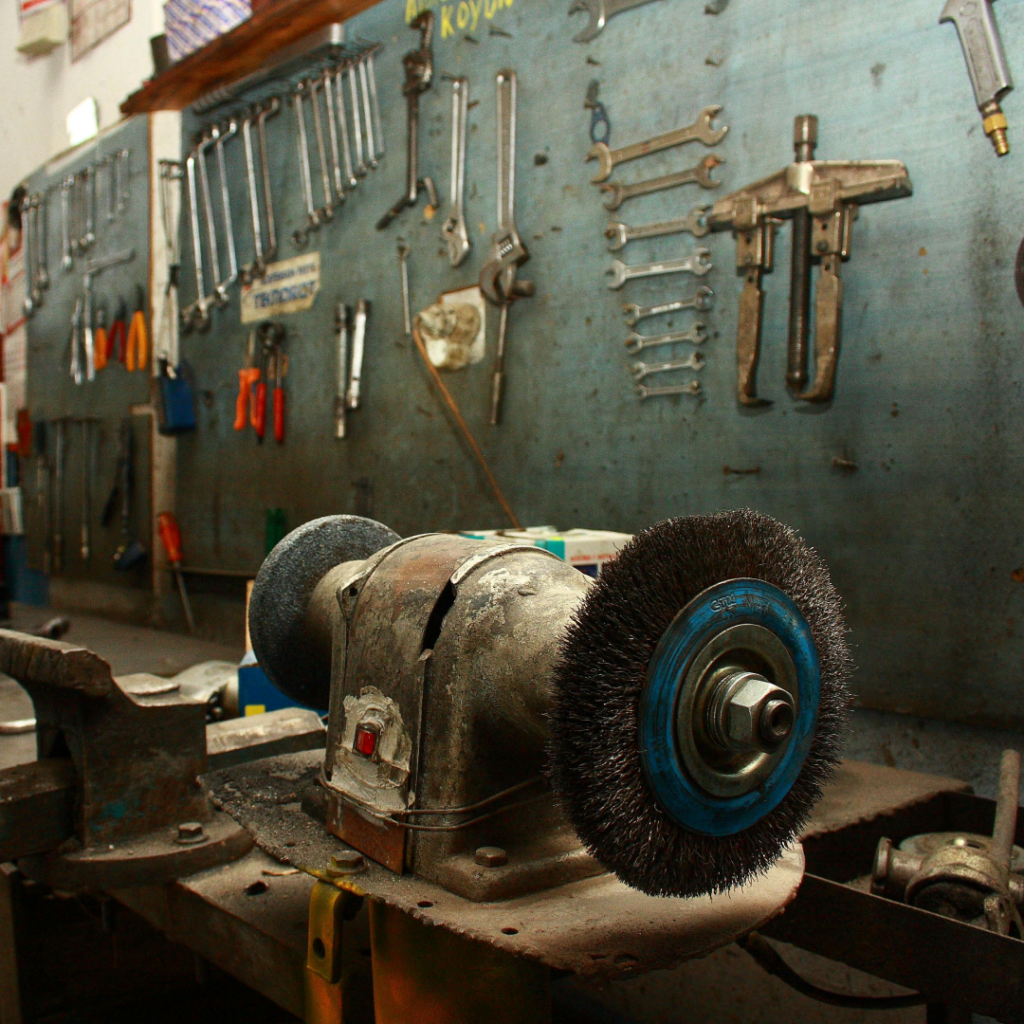 Hand tools on the wall of a workshop next to an electric sander