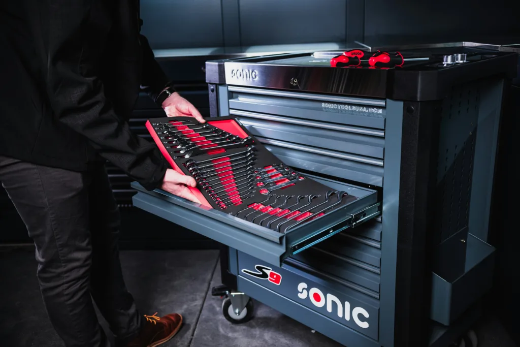 Man putting a set of spanners into a large toolbox