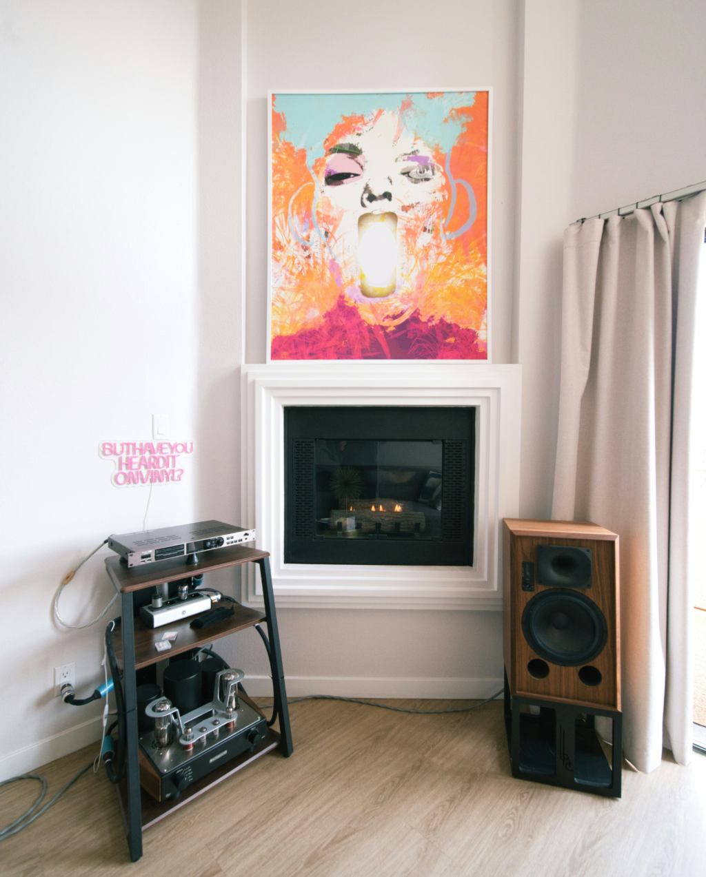 Fireplace with a home audio setup on the left , a speaker on the right and a painting above
